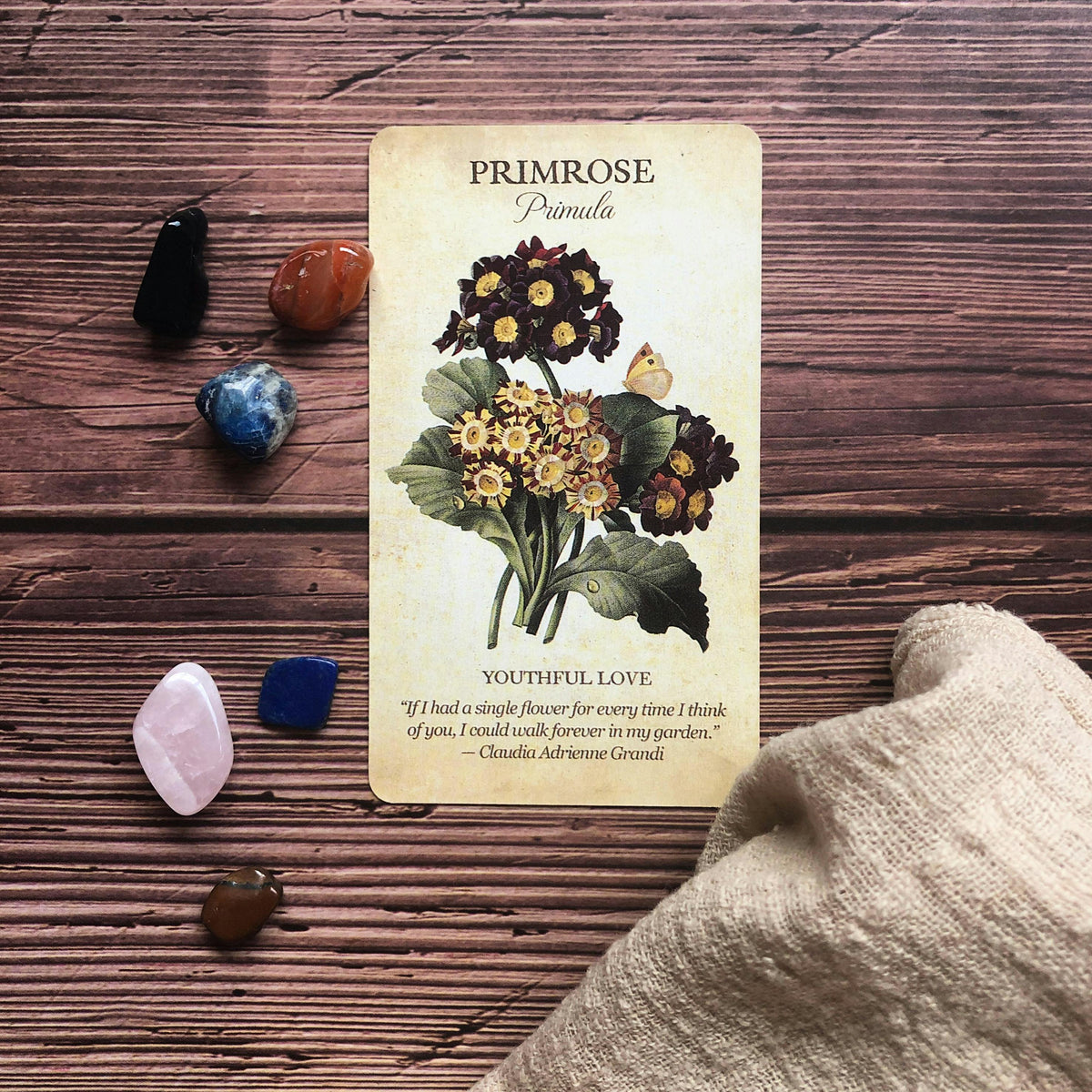 Card with floral design and text on a wooden surface with crystals and fabric.